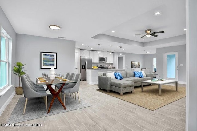 living room with a healthy amount of sunlight, ceiling fan, and light hardwood / wood-style floors