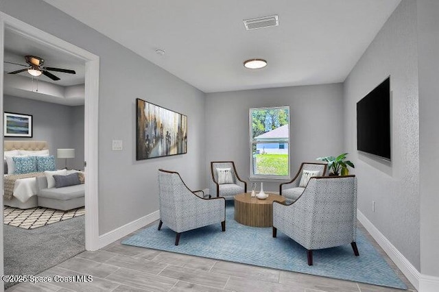 sitting room featuring ceiling fan and light colored carpet