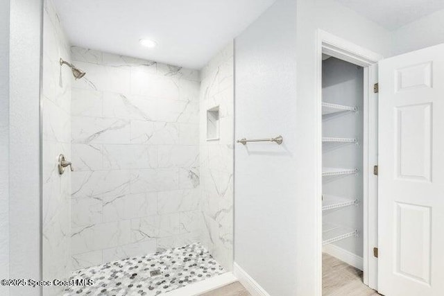 bathroom with tiled shower and hardwood / wood-style floors