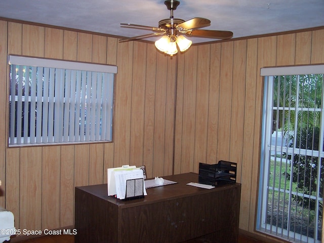 unfurnished office featuring ceiling fan and wooden walls