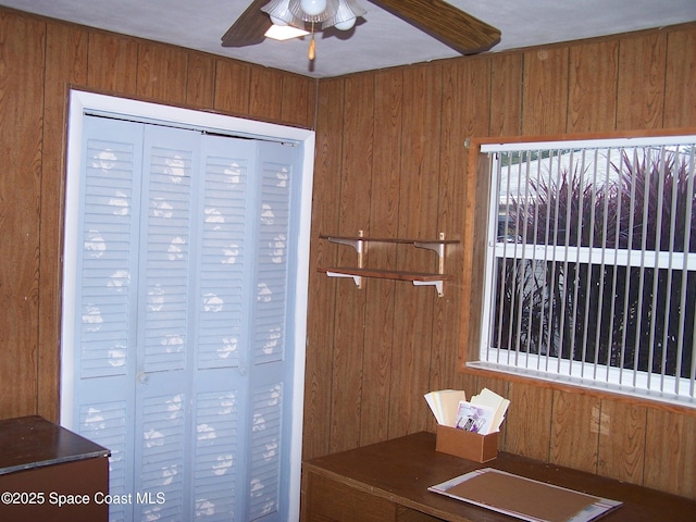 unfurnished office with ceiling fan and wood walls