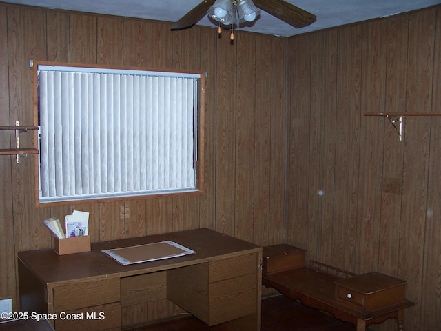 office space featuring ceiling fan and wooden walls