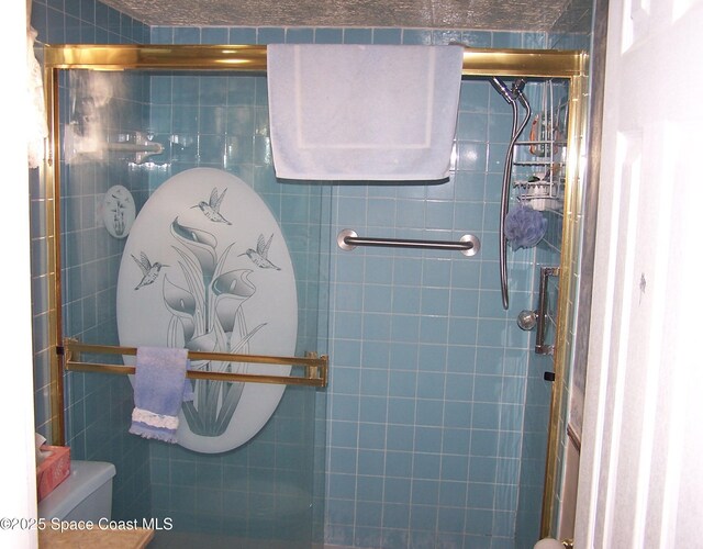 bathroom with tile walls, a shower with door, and toilet