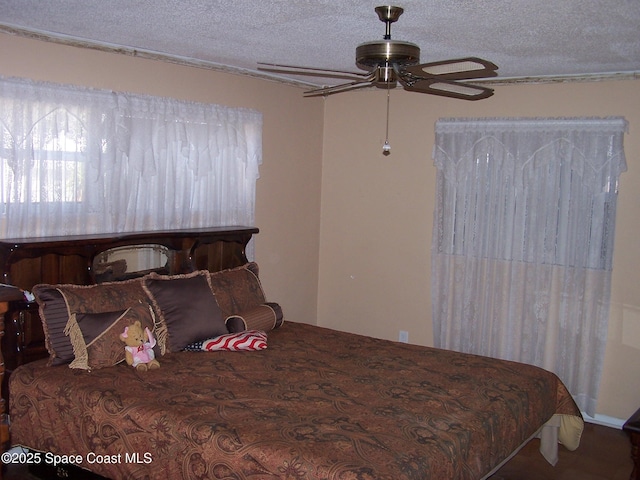 bedroom with ceiling fan and a textured ceiling