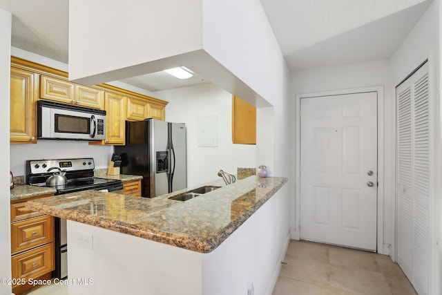 kitchen featuring kitchen peninsula, appliances with stainless steel finishes, light stone countertops, sink, and light tile patterned flooring