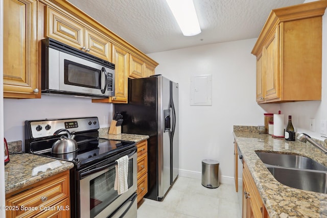 kitchen with light stone countertops, sink, a textured ceiling, and appliances with stainless steel finishes