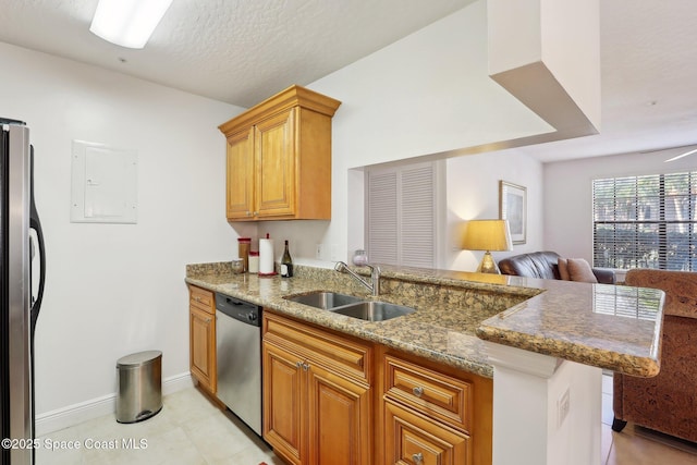 kitchen featuring sink, light stone counters, kitchen peninsula, light tile patterned flooring, and appliances with stainless steel finishes