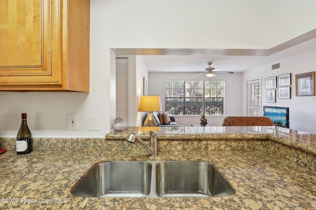 kitchen featuring stone countertops, ceiling fan, and sink