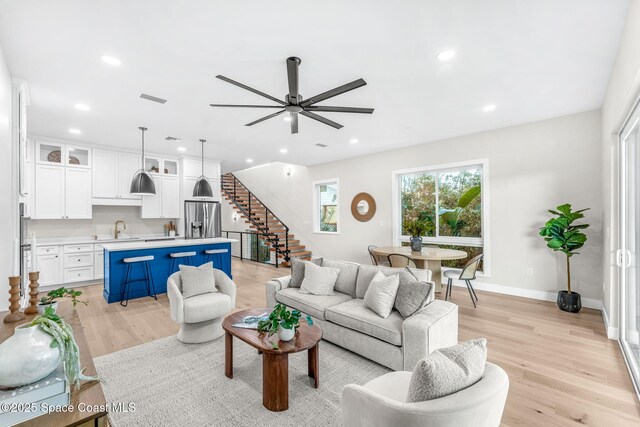 living room featuring light hardwood / wood-style floors, sink, and ceiling fan