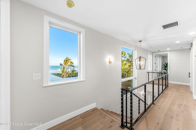 hallway with a water view and light hardwood / wood-style flooring