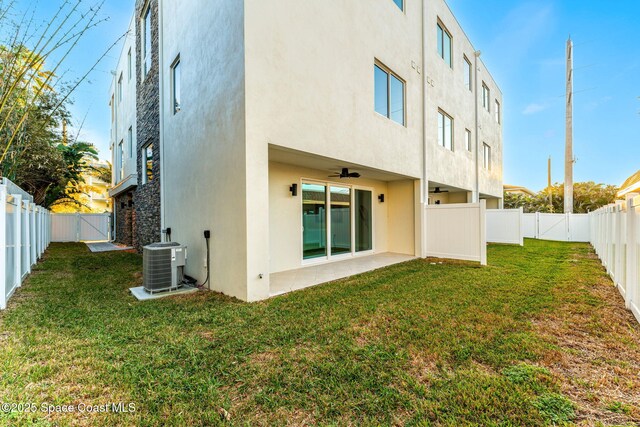 back of property with a lawn, central AC, and ceiling fan