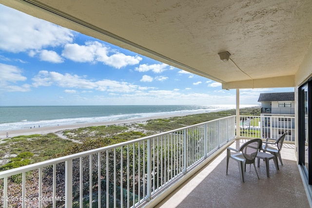 balcony with a water view and a view of the beach