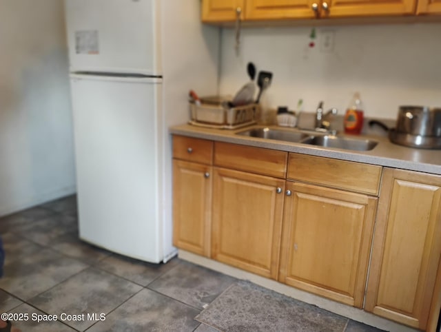 kitchen featuring dark tile patterned flooring, white fridge, and sink