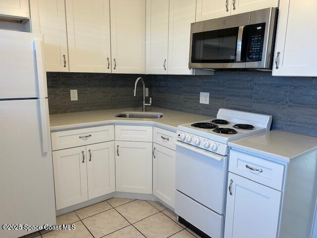 kitchen with white cabinetry, white appliances, sink, and light tile patterned floors