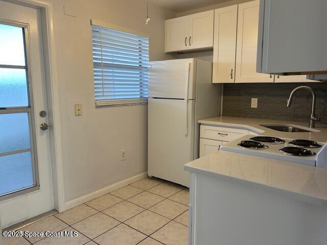 380 N Brevard Ave Unit C-1, Cocoa Beach, FL 32931 - kitchen with white appliances, light countertops, backsplash, and white cabinetry