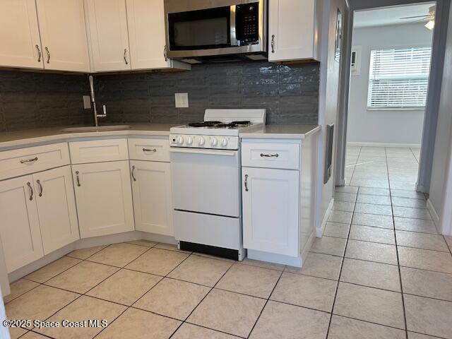 kitchen featuring white cabinets, white stove, tasteful backsplash, and light tile patterned flooring