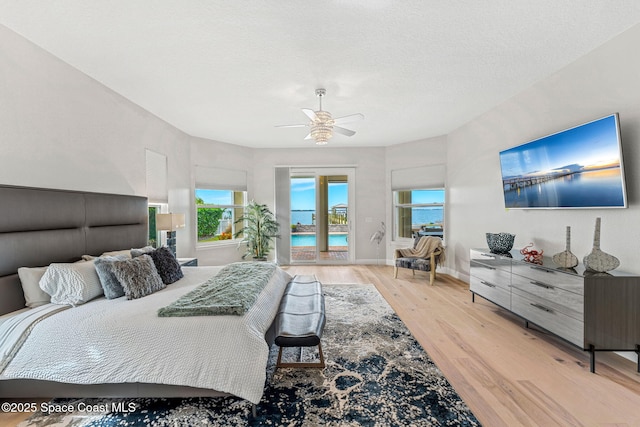 bedroom featuring access to exterior, a textured ceiling, light hardwood / wood-style flooring, and ceiling fan