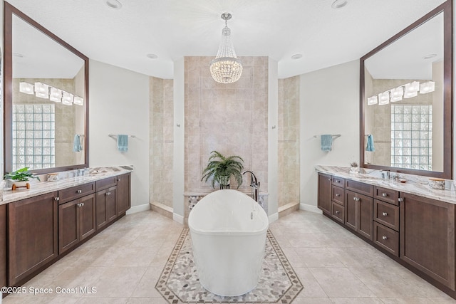 bathroom with an inviting chandelier, vanity, a washtub, tile patterned floors, and a textured ceiling