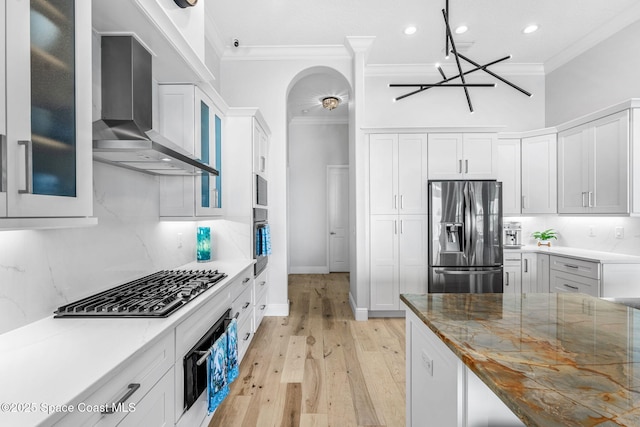 kitchen featuring white cabinets, stainless steel appliances, and wall chimney range hood