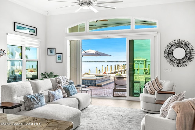 living room featuring light hardwood / wood-style floors, ceiling fan, and a water view