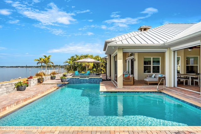 view of swimming pool featuring a patio area, an in ground hot tub, and a water view