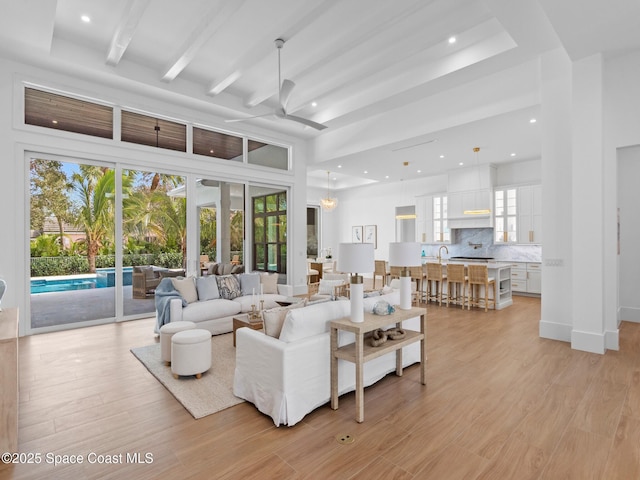 living room featuring beam ceiling, ceiling fan, a healthy amount of sunlight, and light hardwood / wood-style floors