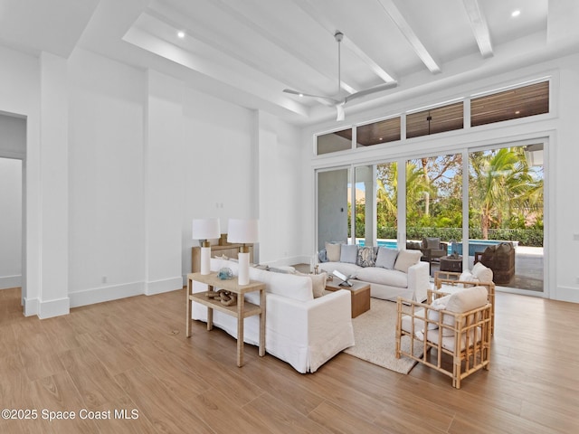 living room with baseboards, light wood finished floors, beam ceiling, a high ceiling, and recessed lighting