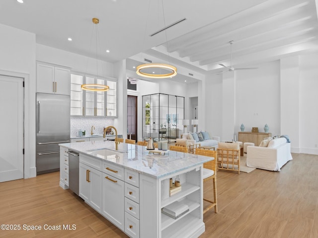 kitchen with light wood-type flooring, open shelves, a sink, stainless steel appliances, and white cabinets