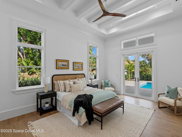 bedroom featuring access to exterior, multiple windows, baseboards, and wood finished floors