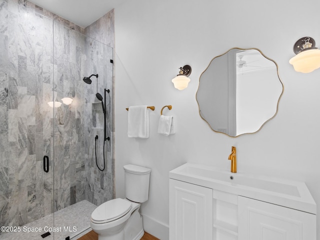 bathroom featuring vanity, toilet, baseboards, and a marble finish shower