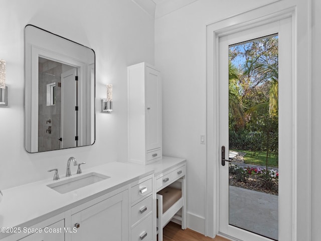 bathroom featuring tiled shower, vanity, and wood finished floors