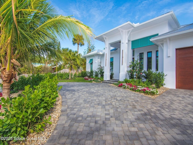 exterior space featuring decorative driveway and stucco siding