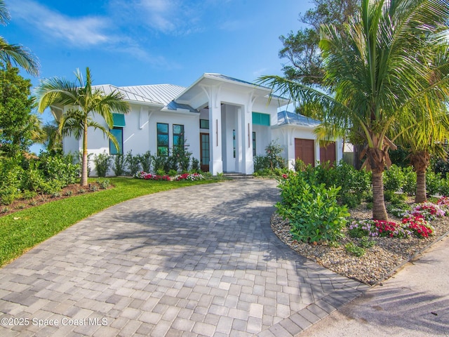 view of front of house featuring stucco siding, metal roof, decorative driveway, an attached garage, and a standing seam roof