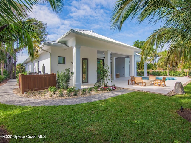 rear view of property featuring stucco siding, a lawn, metal roof, a patio area, and an outdoor pool