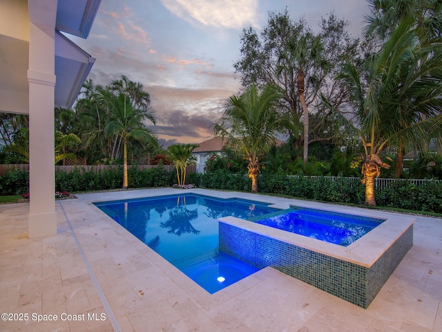 view of swimming pool featuring a pool with connected hot tub, a patio area, and a fenced backyard