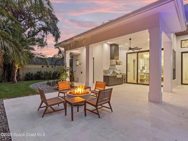 view of patio / terrace featuring fence, exterior kitchen, a ceiling fan, and an outdoor fire pit