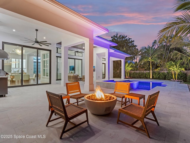 patio terrace at dusk with ceiling fan, area for grilling, a fenced in pool, and an outdoor fire pit