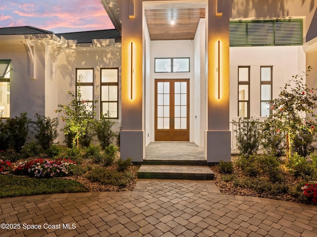 view of exterior entry featuring french doors and stucco siding