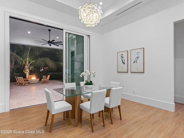 dining area featuring visible vents, baseboards, light wood-style flooring, and ceiling fan with notable chandelier