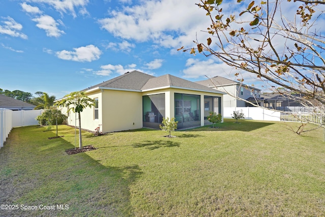 back of property with a lawn and a sunroom