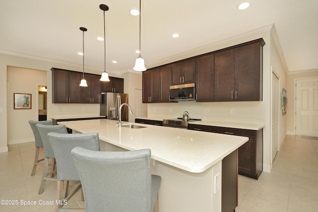 kitchen featuring sink, hanging light fixtures, stainless steel appliances, an island with sink, and dark brown cabinets