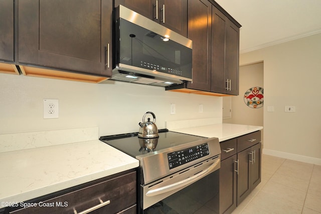 kitchen featuring appliances with stainless steel finishes, light stone counters, dark brown cabinetry, crown molding, and light tile patterned floors