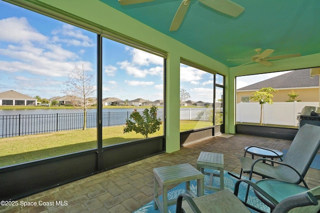 sunroom / solarium featuring a water view and ceiling fan