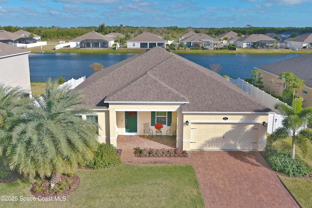 exterior space featuring a porch, a water view, a garage, and a front lawn