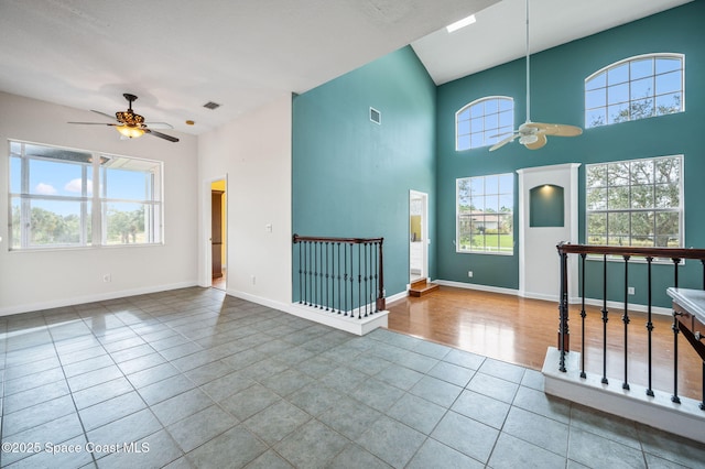 tiled entryway featuring ceiling fan and a towering ceiling