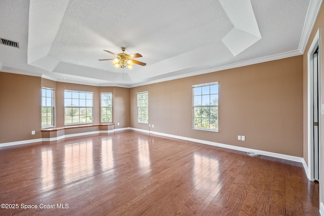 spare room with ceiling fan, dark hardwood / wood-style flooring, a raised ceiling, and plenty of natural light