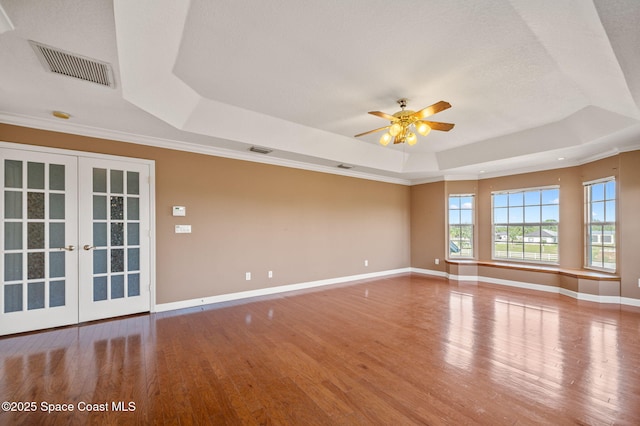 spare room with hardwood / wood-style floors, ceiling fan, french doors, and a tray ceiling