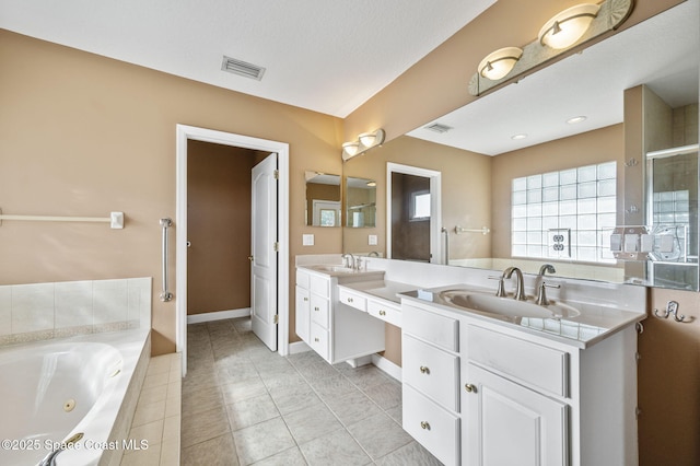 bathroom with tile patterned flooring, vanity, and a relaxing tiled tub