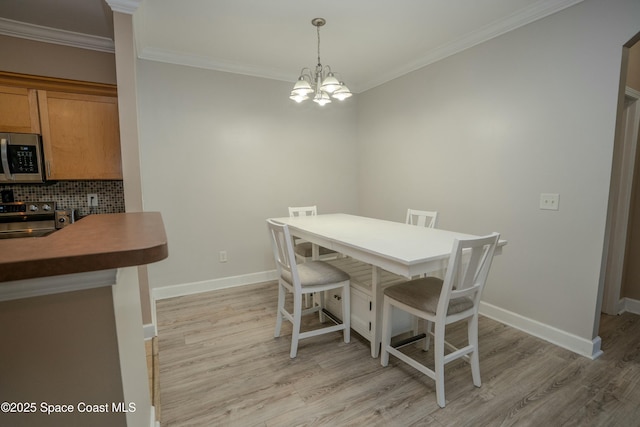 dining space with crown molding, light hardwood / wood-style floors, and an inviting chandelier