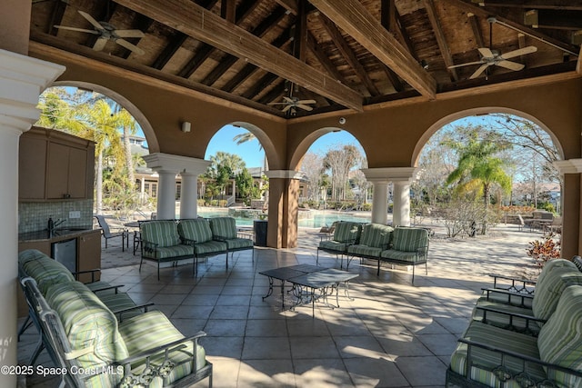 view of patio with an outdoor living space, ceiling fan, a community pool, and exterior kitchen